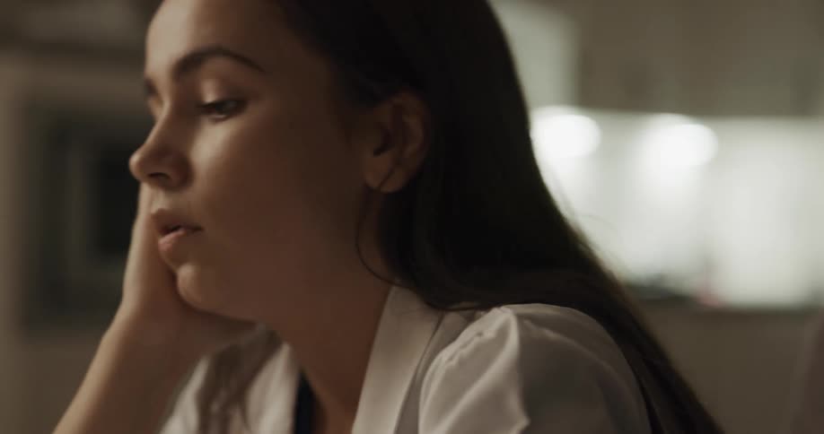 A woman with a lab coat removing a mask and a stethoscope