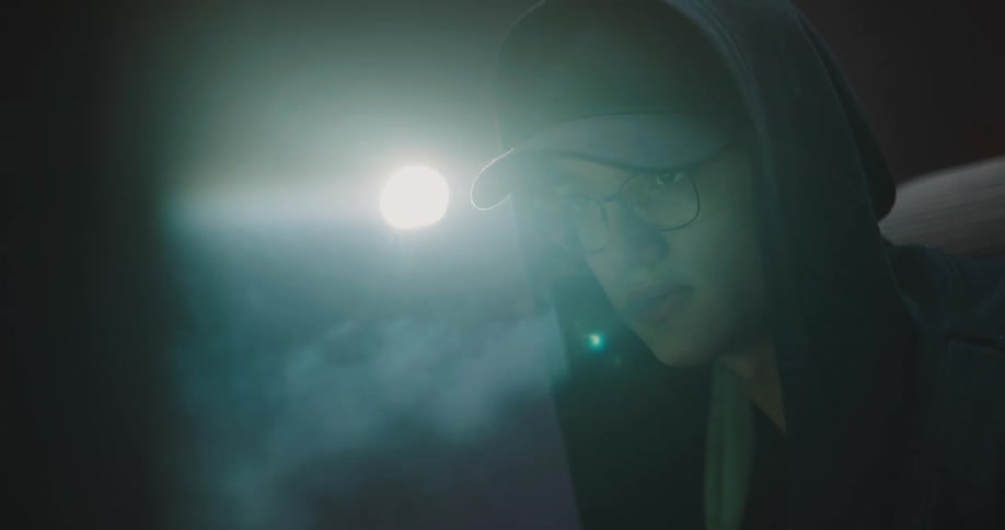 A teenage boy sits in the dark and vapes
