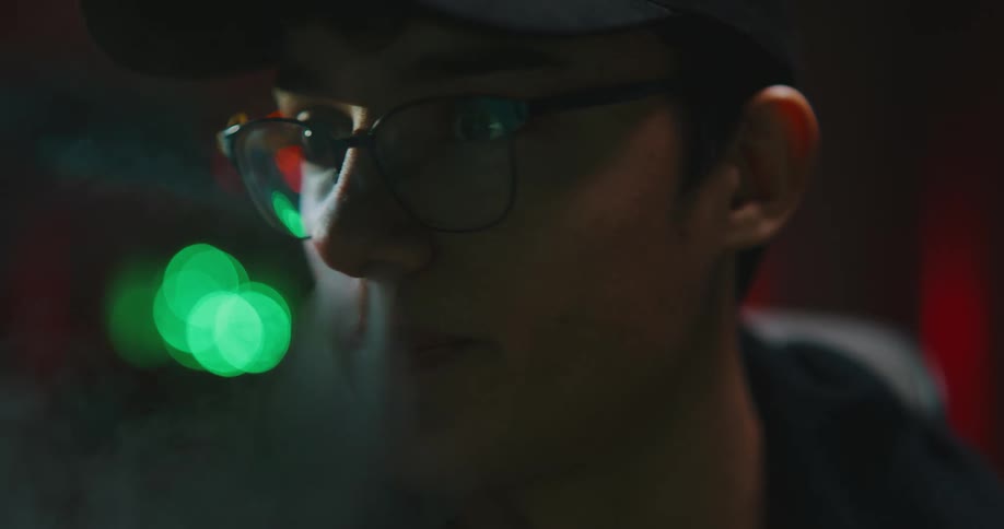 A man in a room with a hat hoodie and glasses with smoke coming out of his nose
