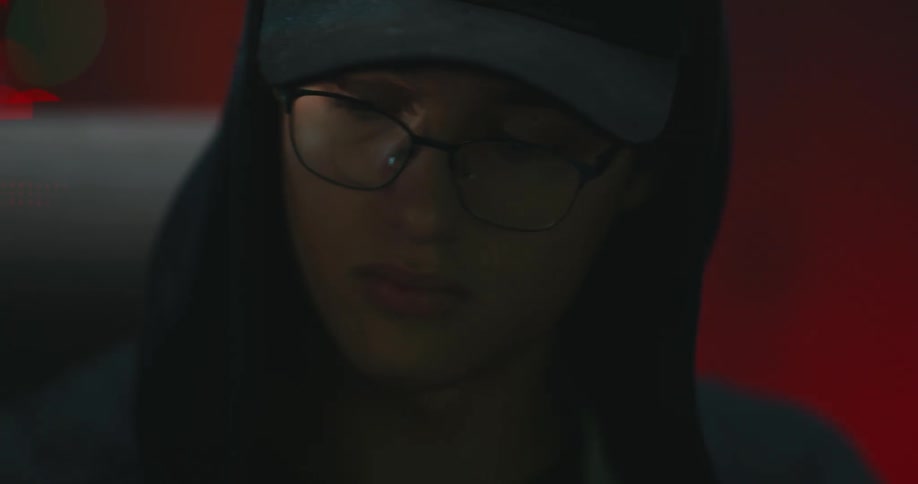 Man wearing baseball cap and hoodie inserts chip into slot of circuit board