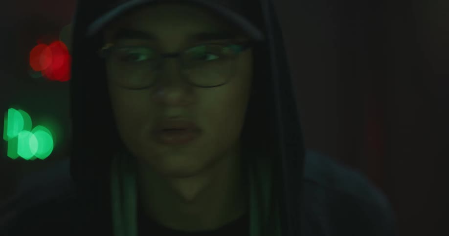 A teenage boy looks form side to side in a dark room