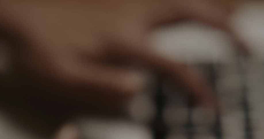 Close up of a womans fingers as she types on a laptop