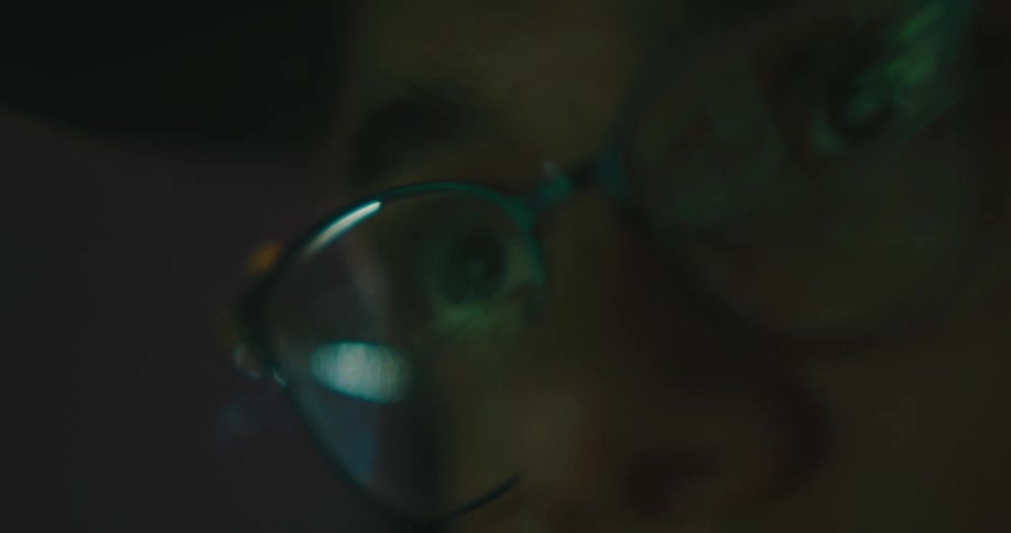 A person looking at something on a screen with the reflection in their glasses