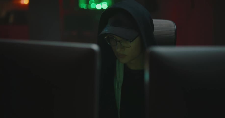 A man in a room sitting at a desk typing on a keyboard on a computer