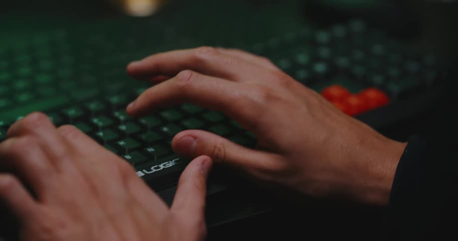 A person in a room typing on a keyboard next to a mouse