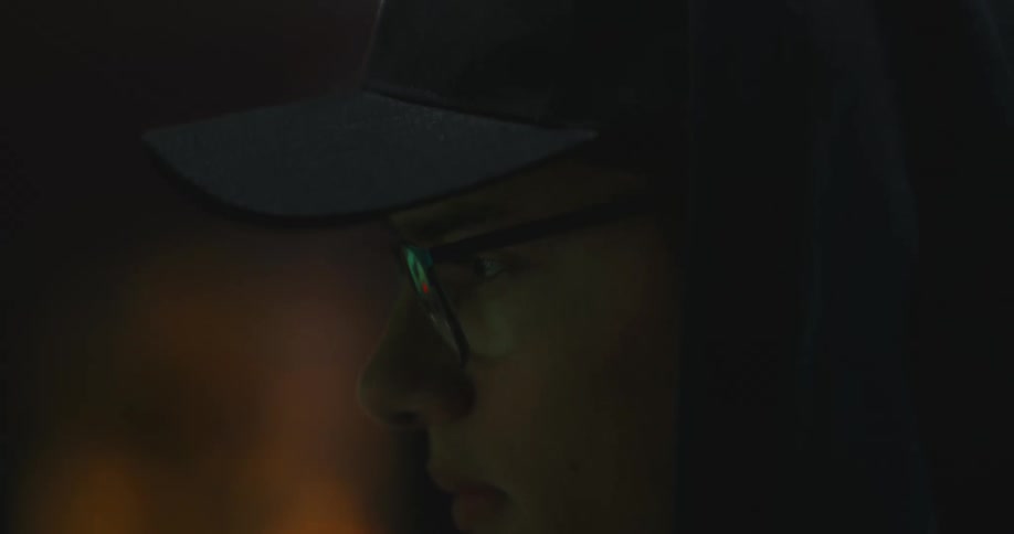 A man with a hat hoodie and glasses sitting in a room