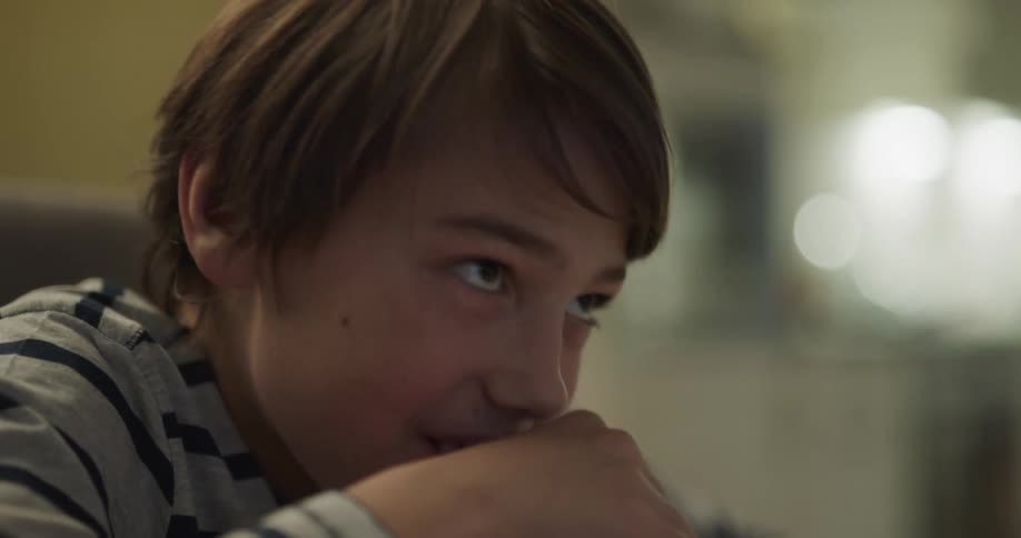 A boy laughs while making a mess eating cookies in the kitchen