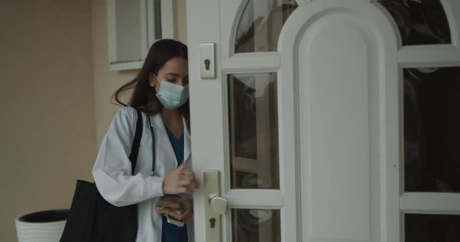 Female medial professional walking into a house and closing front door