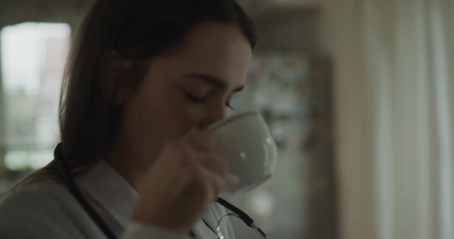 A doctor is drinking a cup of coffee indoors
