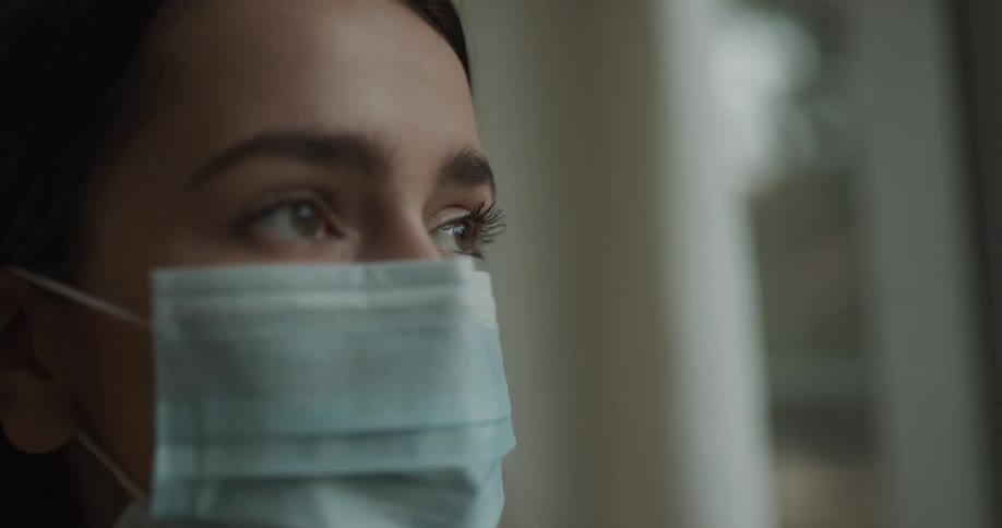 A woman wearing a mask staring and blinking