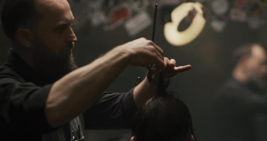 A man in a barbershop cutting another mans hair with a mirror in the background