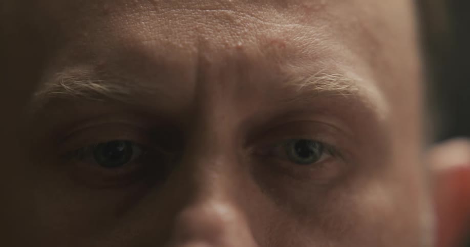 A man in a room staring and cutting hair