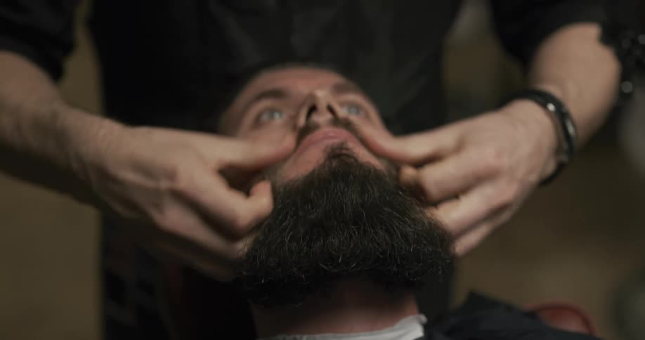 A man is having his beard sculpted in the shop