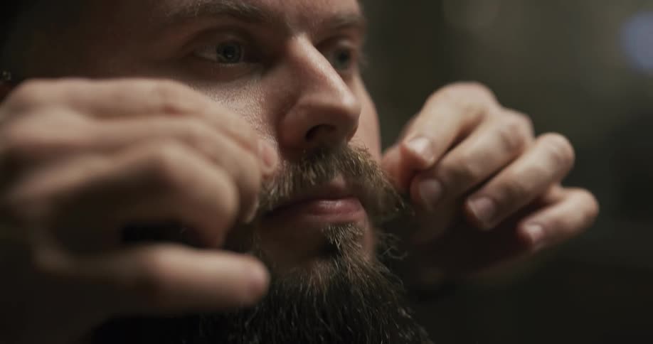 Barber twirls ends of bearded mans mustache