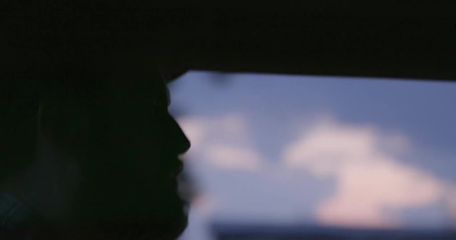 White man wearing a hat and driving a car at a residential neighborhood