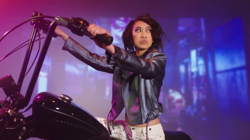 A woman is sitting on a parked motorcycle thats on display