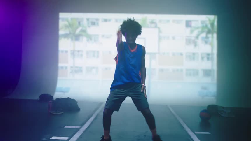 A young man dances in front of a wall on which a series of images are being projected