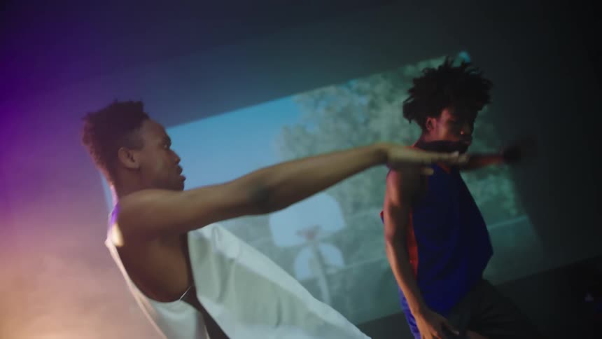 Two boys on a stage dancing with images projecting in the background