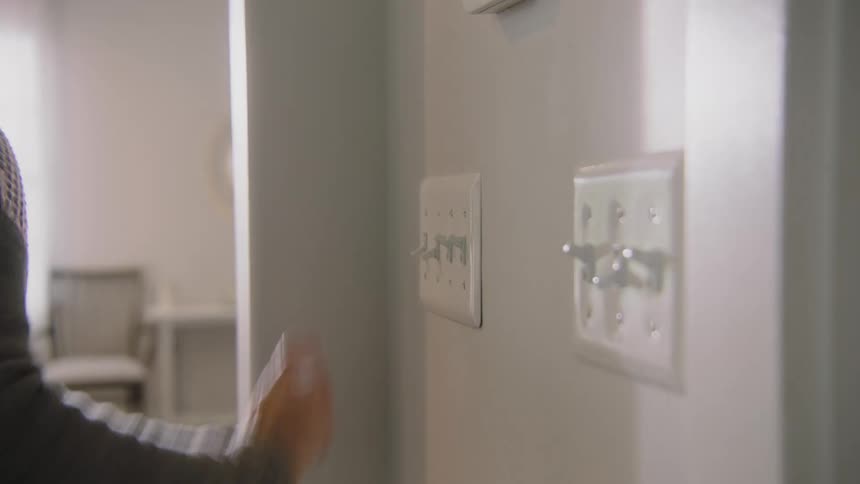 A woman flips onlight switches in her home
