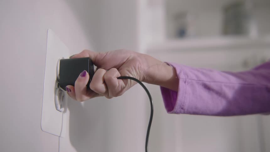 A person plugs a wire into the wall