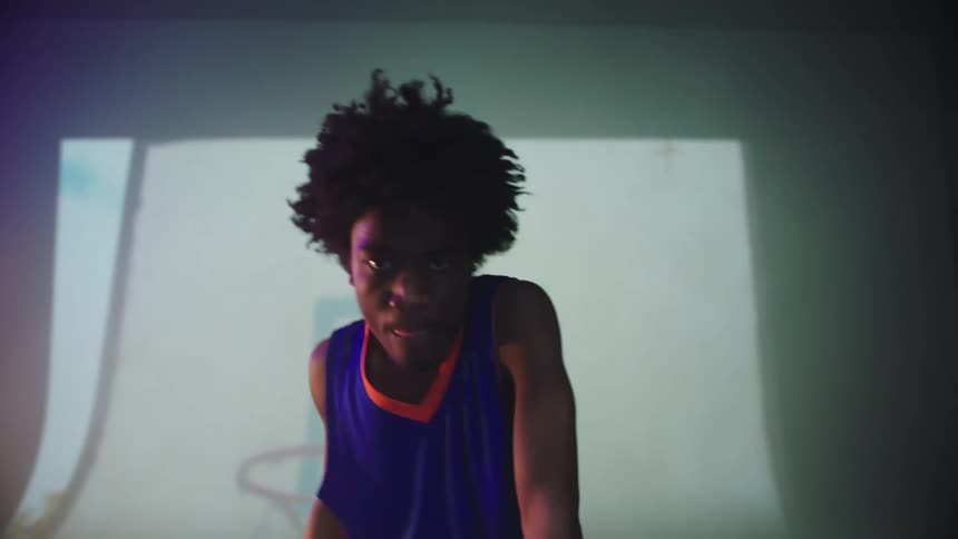 A person is dancing indoors by a display screen