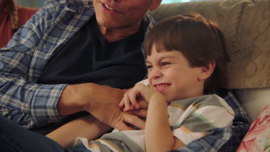 A mother and father playing with their son on a couch