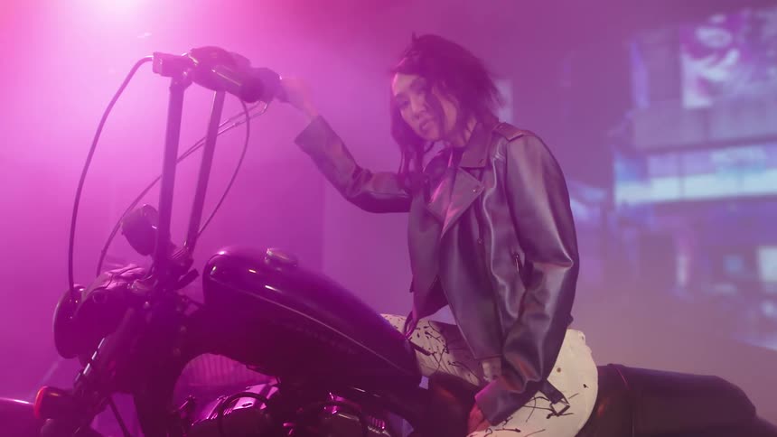 A woman sitting on a motorcycle on a stage with lights flashing