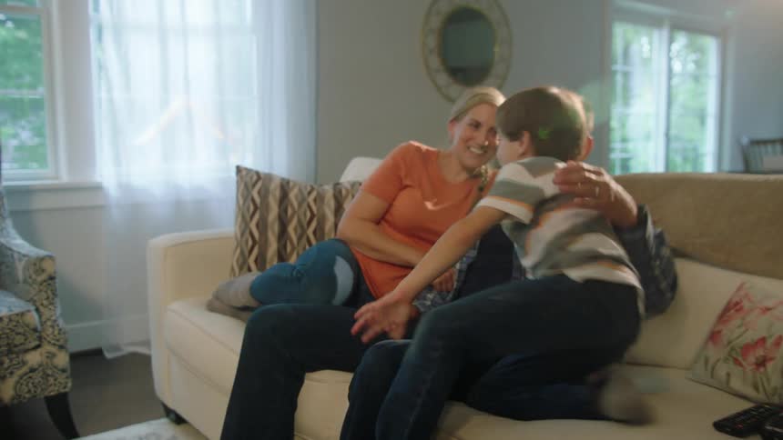 A boy gets up from playing with his siblings to sit on a couch with his parents