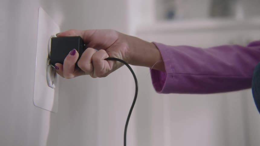 A person crouches to plug something in
