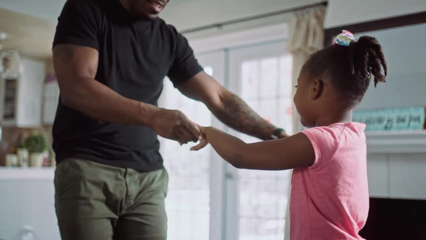 Father dancing with his little daughter in the livingroom at home