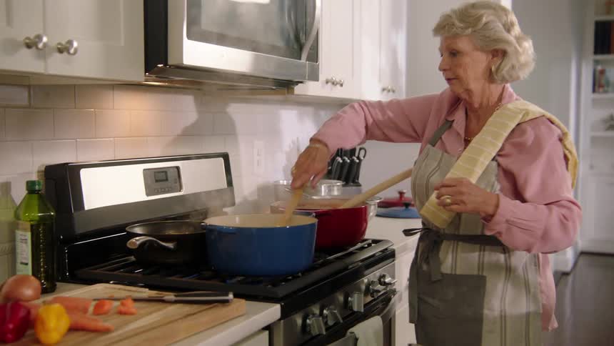 A woman cooking food in a pot on a stove