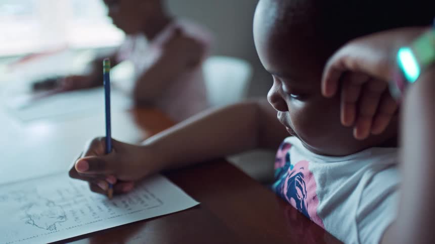 Two young black girls working on schoolwork at table in home
