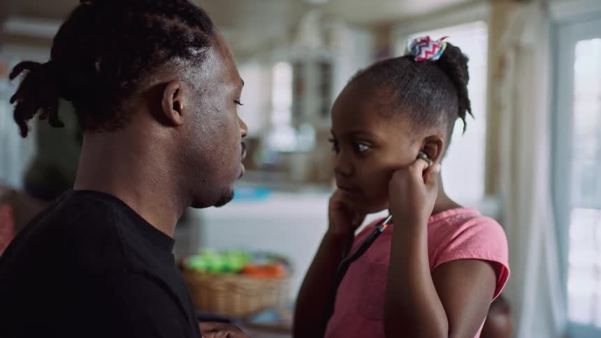 A girl with a stethoscope listening to a mans heart with a door and a window in the background