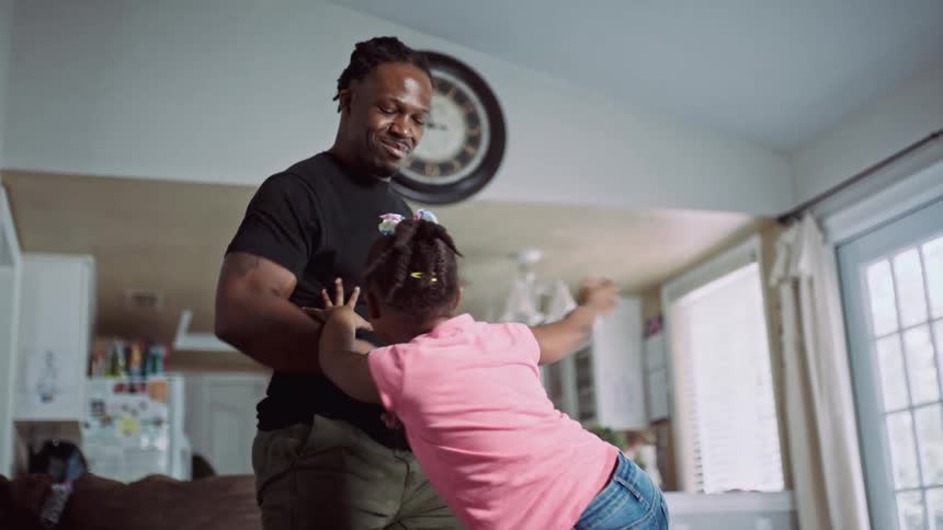 Father and daughter dance in living room
