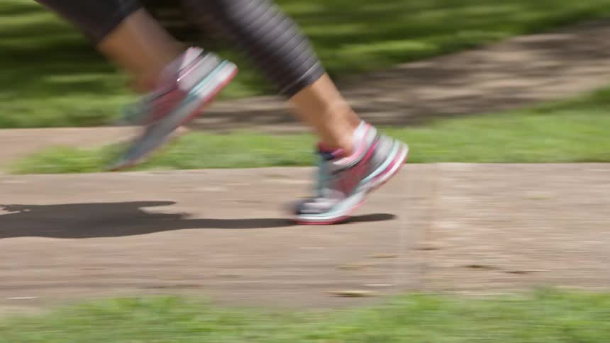 Person jogging along a city sidewalk