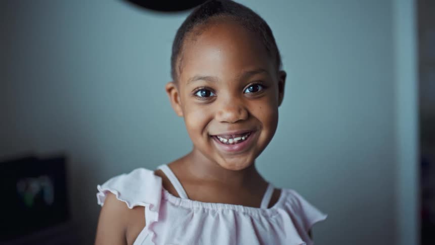 Black girl smiling while standing alone in a room