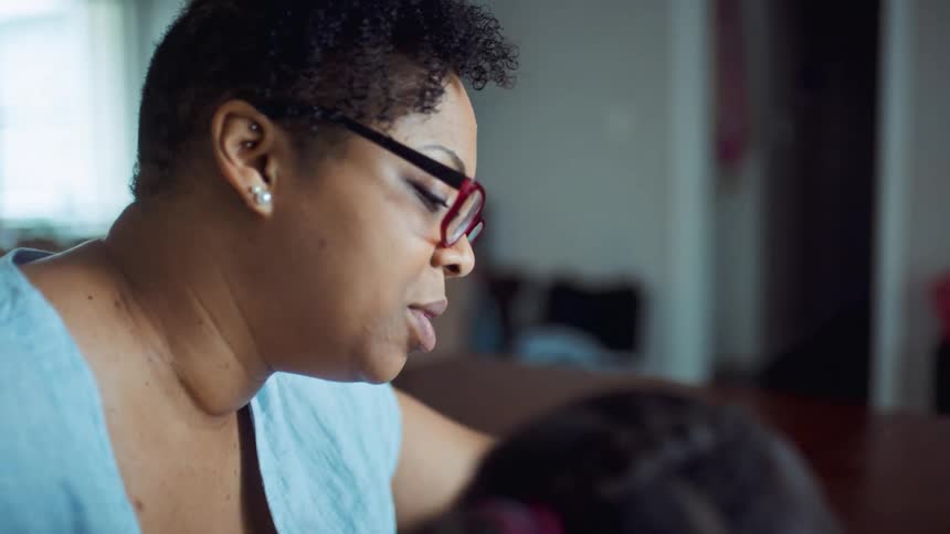 Mother helping her daughter study and read at home