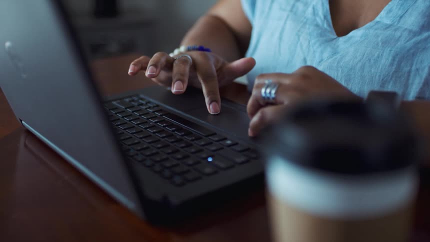 A woman in a room sitting at a table using a laptop