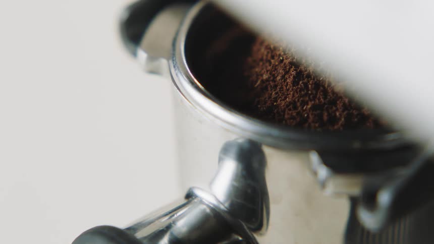 Ground coffee beans fill the basin of a metal grinder
