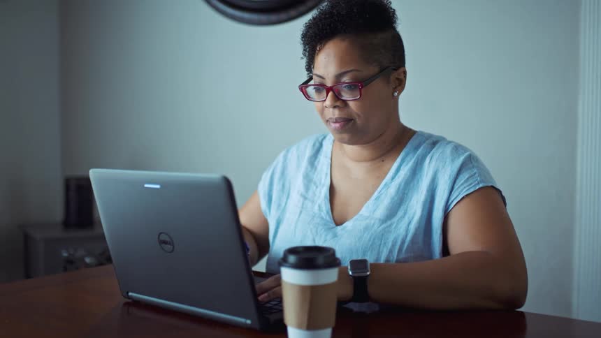Woman typing on her laptop alone while sitting at the table