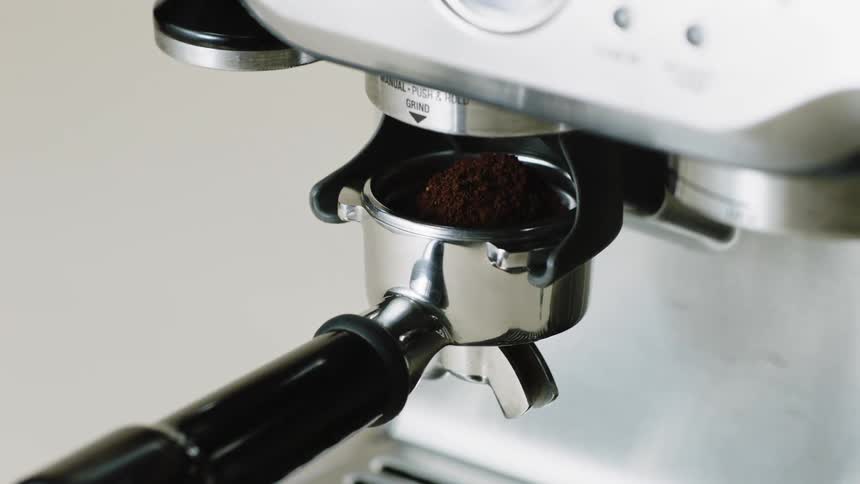 A machine automatically grinds espresso and its collected below to be compacted and brewed
