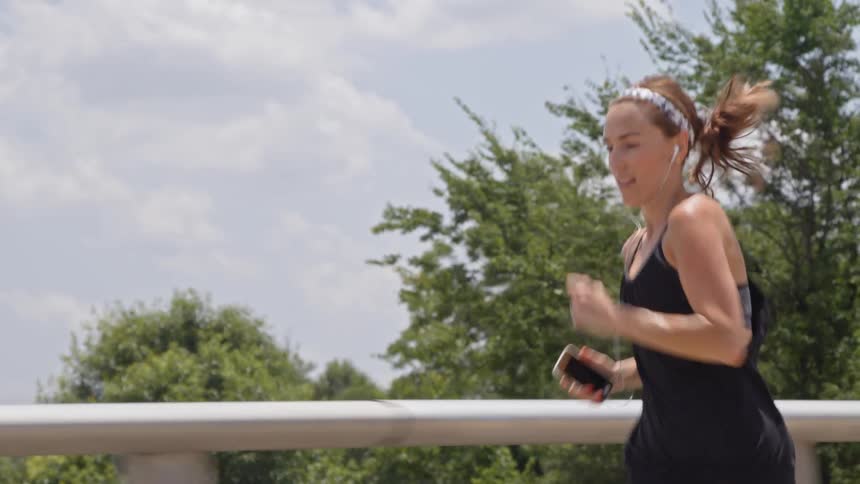A woman is running outside holding her phone