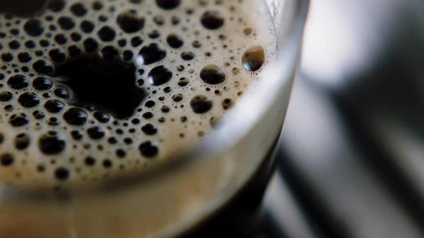 Coffee dripping into a glass with bubbles and smoke