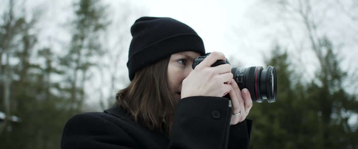 White woman wearing winter clothing taking pictures of the nature with a professional camera