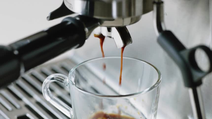 A coffee maker dripping coffee in a glass mug
