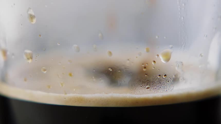 Coffee drips into a glass mug and steams up the sides