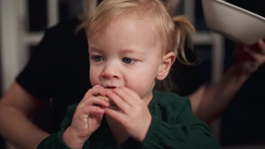 A woman gives her grand daughter a cookie and she smiles and eats it