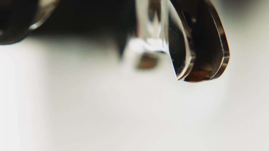Remnants of espresso drip from the spout of an espresso machine