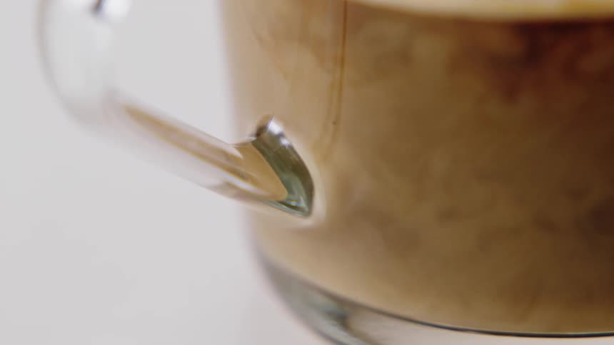 Cream being added to a glass of coffee