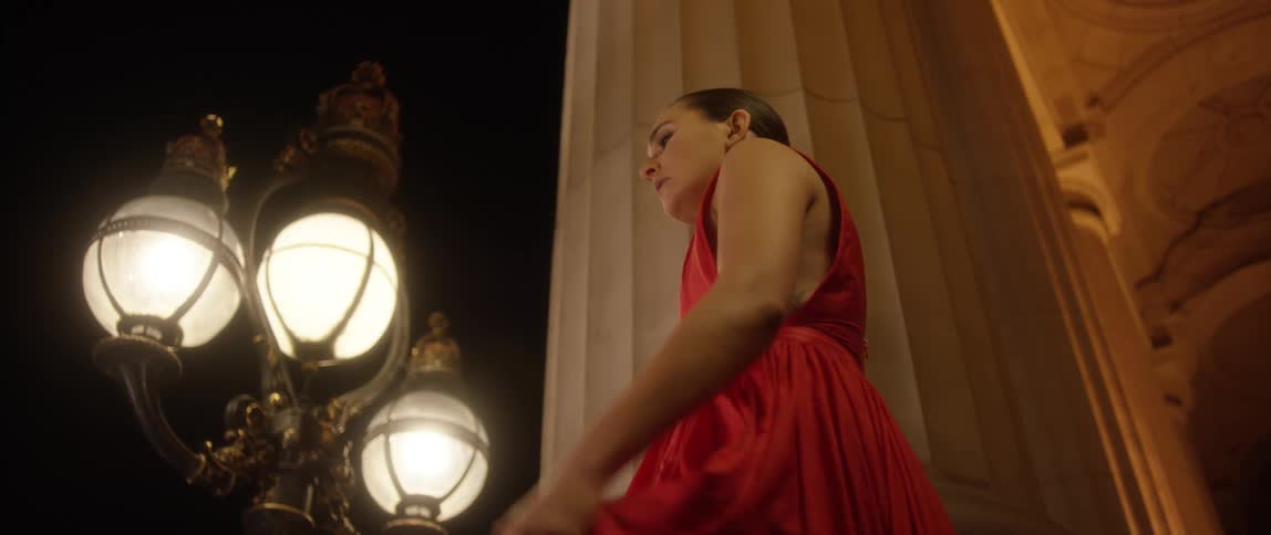 A woman in a dress walking outside near a pillar